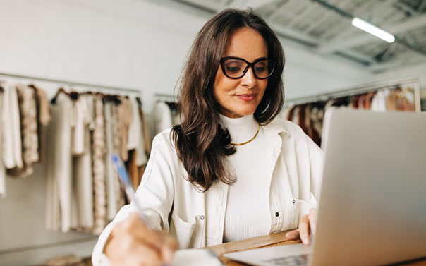 Female owner of boutique store on laptop taking notes